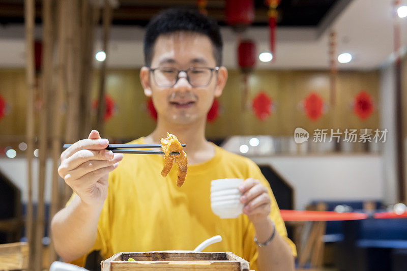 一个亚洲男人在餐馆用筷子夹起一种叫鸡爪酱油的广东dum sum的特写